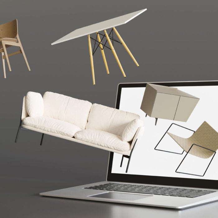 An open laptop on a grey background. Minimalist furniture, including a white sofa, a wood-legged table, and a plywood chair, are floating out of the screen, symbolizing the concept of online furniture shopping.